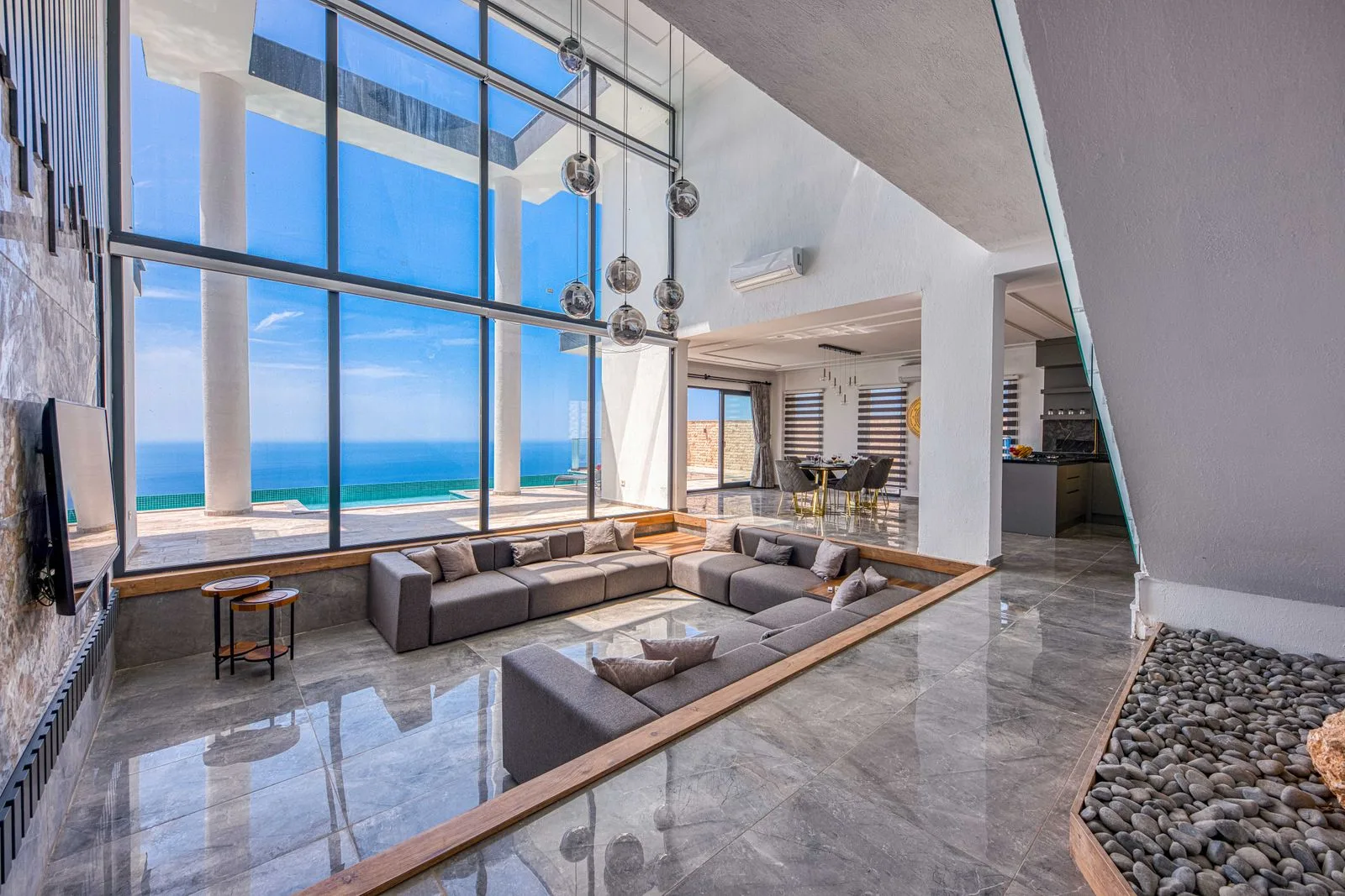 Double-height glass wall framing an open ocean horizon from a sunken living room