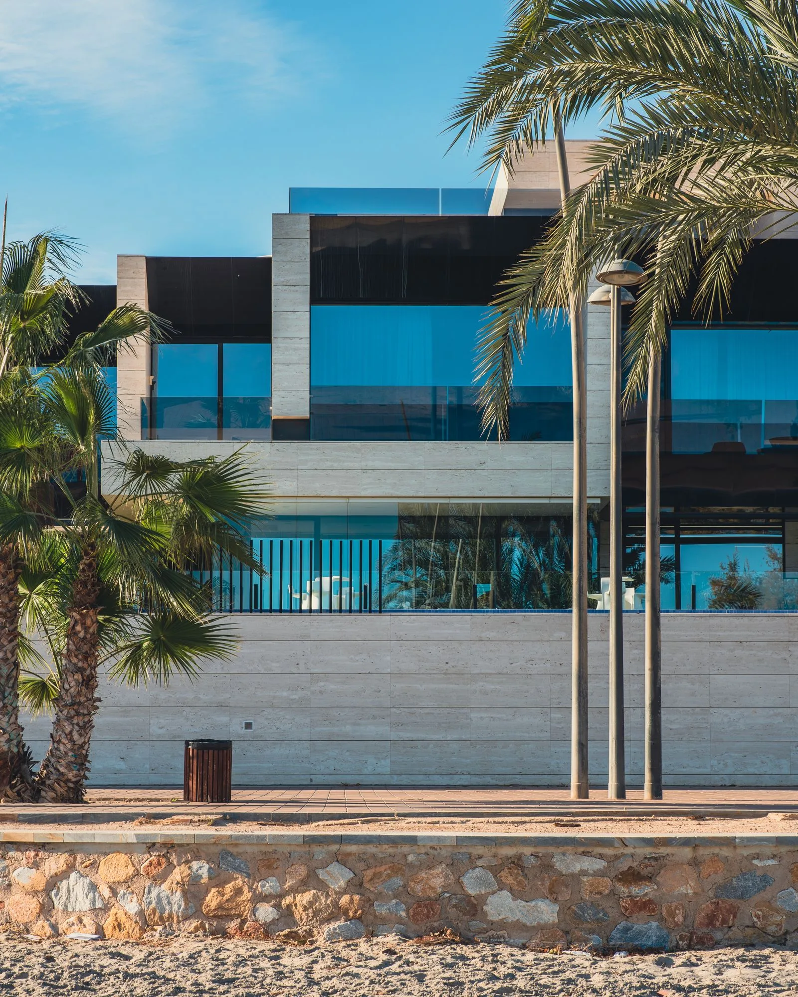 Travertine beachfront residence with full-height glazing among palms