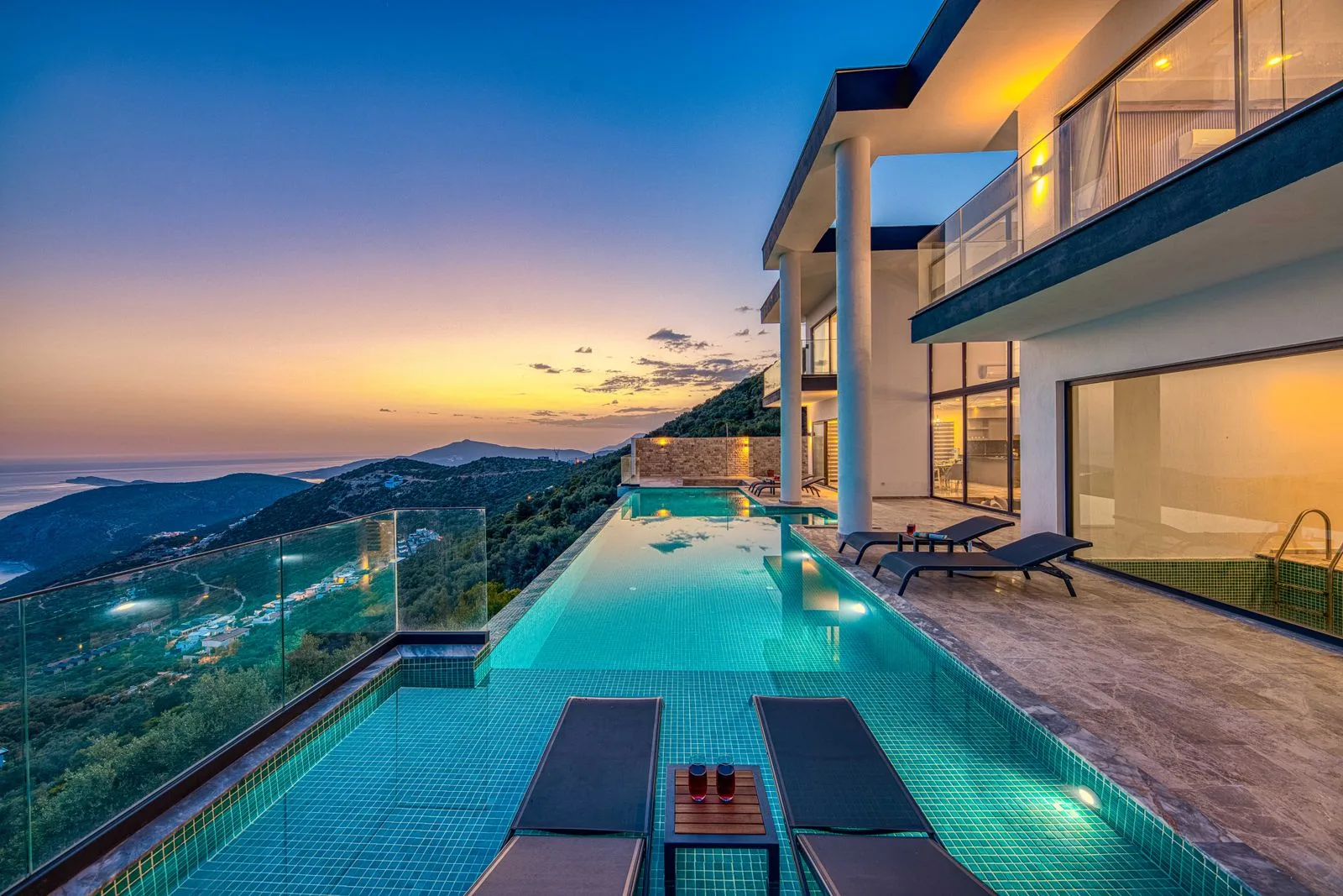 Twilight infinity-pool terrace with glass balustrades overlooking the sea